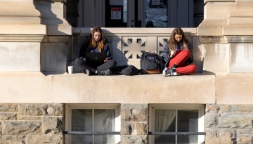 Students study outside of Sibley Hall on a warm winter day.
