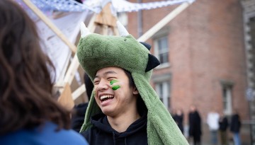 A student with face paint and a dragon hat. 
