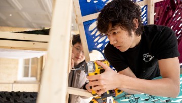 A student using a drill to build the dragon's frame.