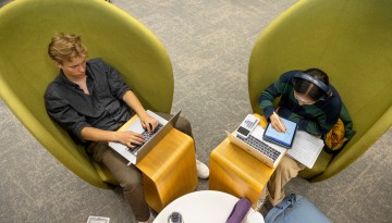 Students work in the big green chairs in Mann Library.