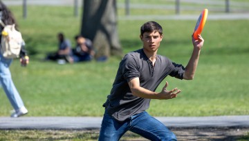 Students play frisbee on the Arts Quad on a warm spring day.