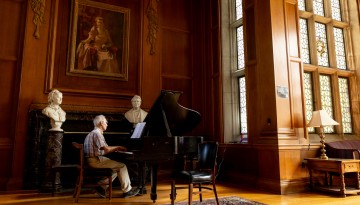 A parent of a Cornell alum records piano music for a friend in Anabel Taylor Hall.