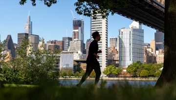 A runner passes along the East River waterfront with Cornell Tech campus in the background.