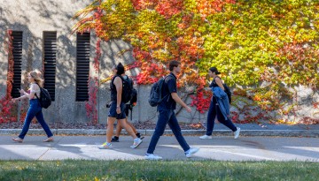 Students pass by an evolving fall canvas on Uris Hall.