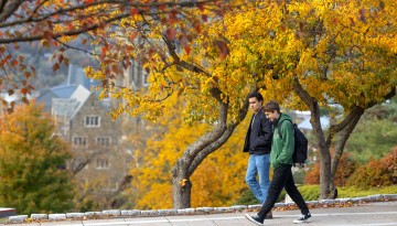 Students walk between Willard Straight Hall and Uris Library on an autumn day.