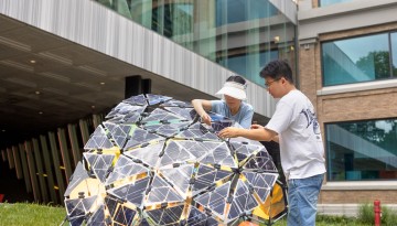 Graduate students in the Jenny Sabin lab secure solar panels to a structure outside Rand and Milstein halls.