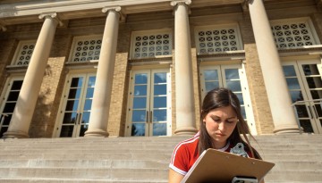 A student does a class assignment near Bailey Hall.