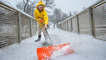 An employee clears snow from the Beebe Dam bridge.