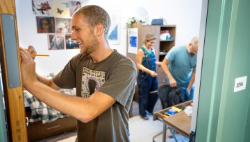 A student writes on his dorm room door. 