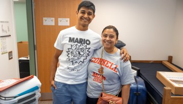 A mom and son pose in a dorm room. 