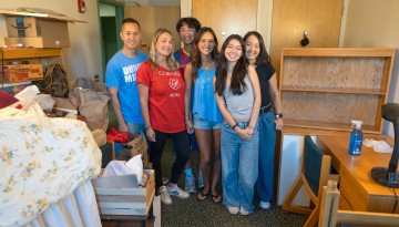 A family poses in a half-empty dorm room. 