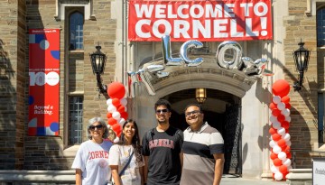 A family poses in front of Willard Straight Hall. 