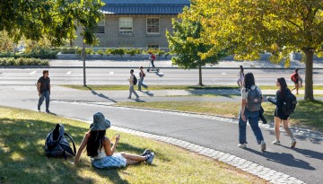 Students enjoy the warm afternoon sun along Feeney Way.