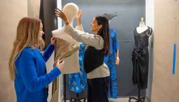 Tabitha Mueller-Schrader ’26, left, and Maya Abrol ’26 prepare uniforms for the “Fit for Duty” exhibition in the HumEc Building.