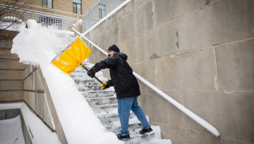 A building care staffer clears steps near Mann Library.