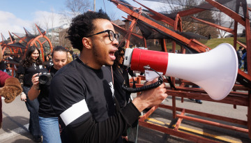 A student on a megaphone walking with the dragon. 