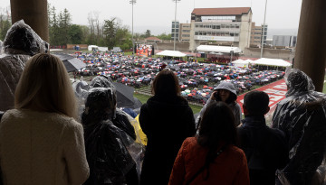 Families in rain gear looking out at the field. 