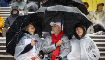A family in the stands under umbrellas. 