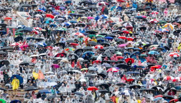 The stands full of families huddling under umbrellas. 