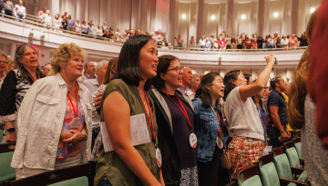 Reunion 2026 attendees stand in an auditorium