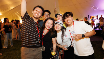 Reunion attendees pose under a tent at night