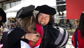 Two graduates share an embrace.