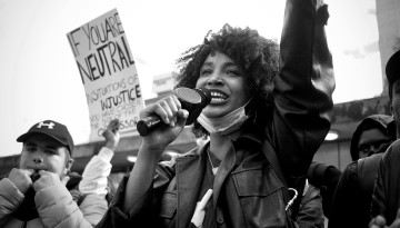 Woman with microphone stands at a racial justice protest