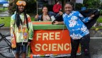 Three kids stand around a table with a banner reading, "Free Science"